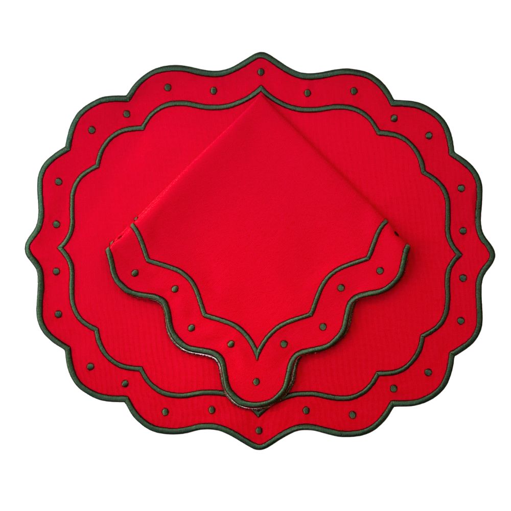 A set of red fabric placemats with scalloped edges and dark green trim, arranged in a nested stack on a plain white background.