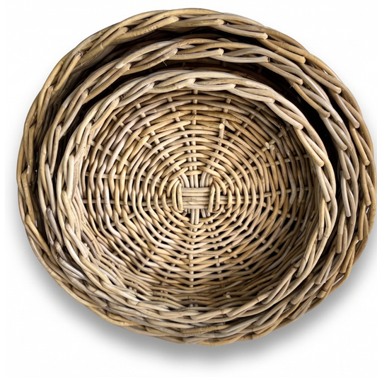 Three nested round woven baskets made from natural light brown wicker or rattan, shown from a top-down view on a white background.