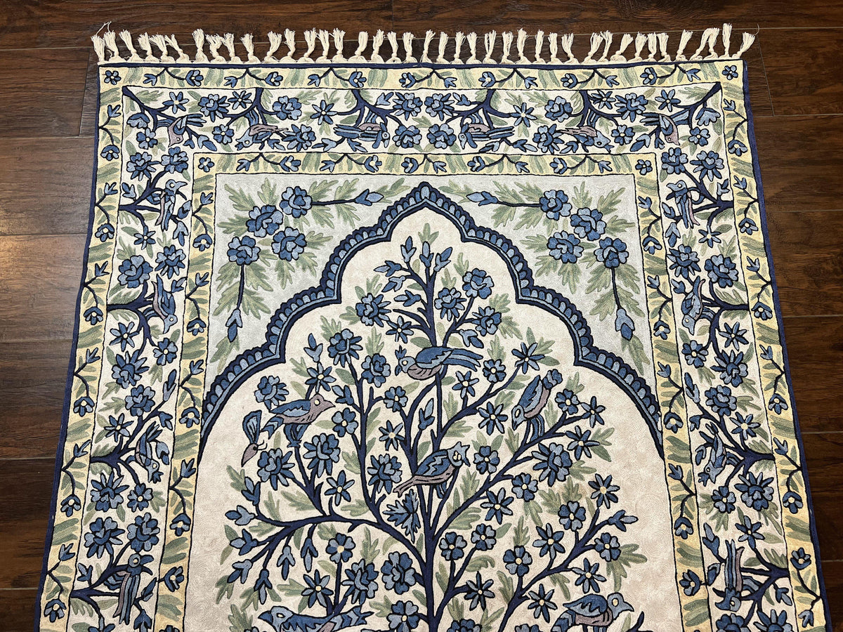Decorative rug with blue floral and bird pattern on a wooden floor