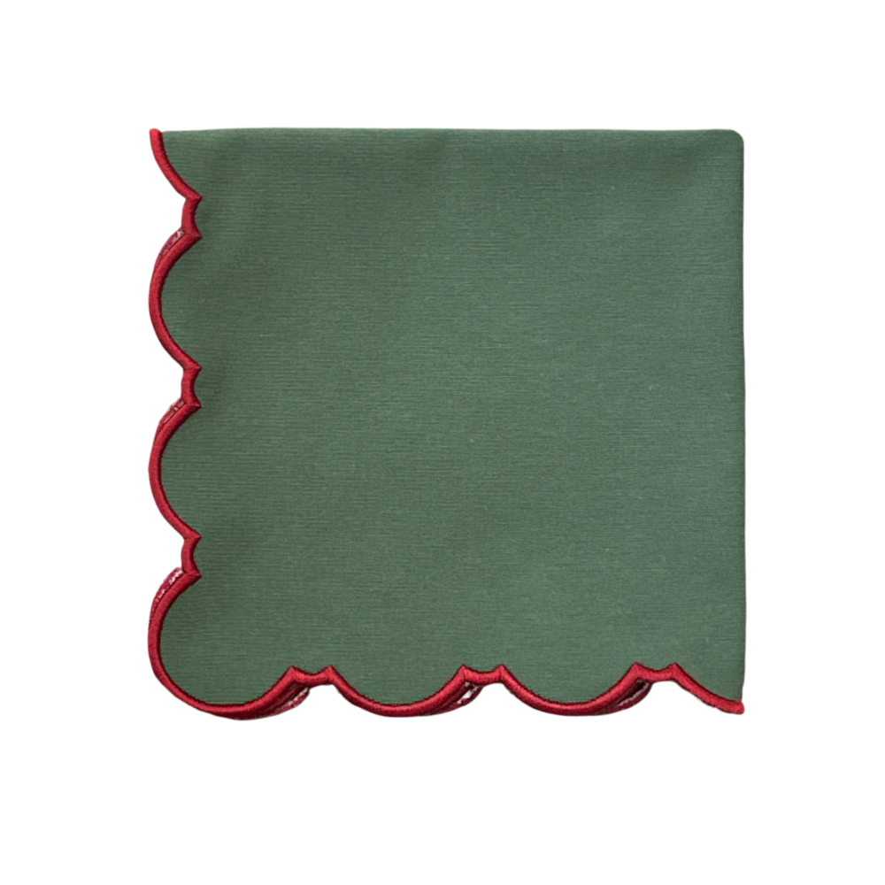 A square green fabric napkin with a scalloped edge trimmed in red, shown flat against a plain white background.