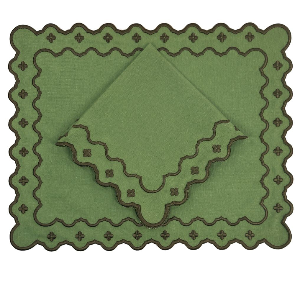 A set of olive green table linens, including a rectangular placemat and two folded napkins, all featuring scalloped edges with a dark brown embroidered cross pattern.