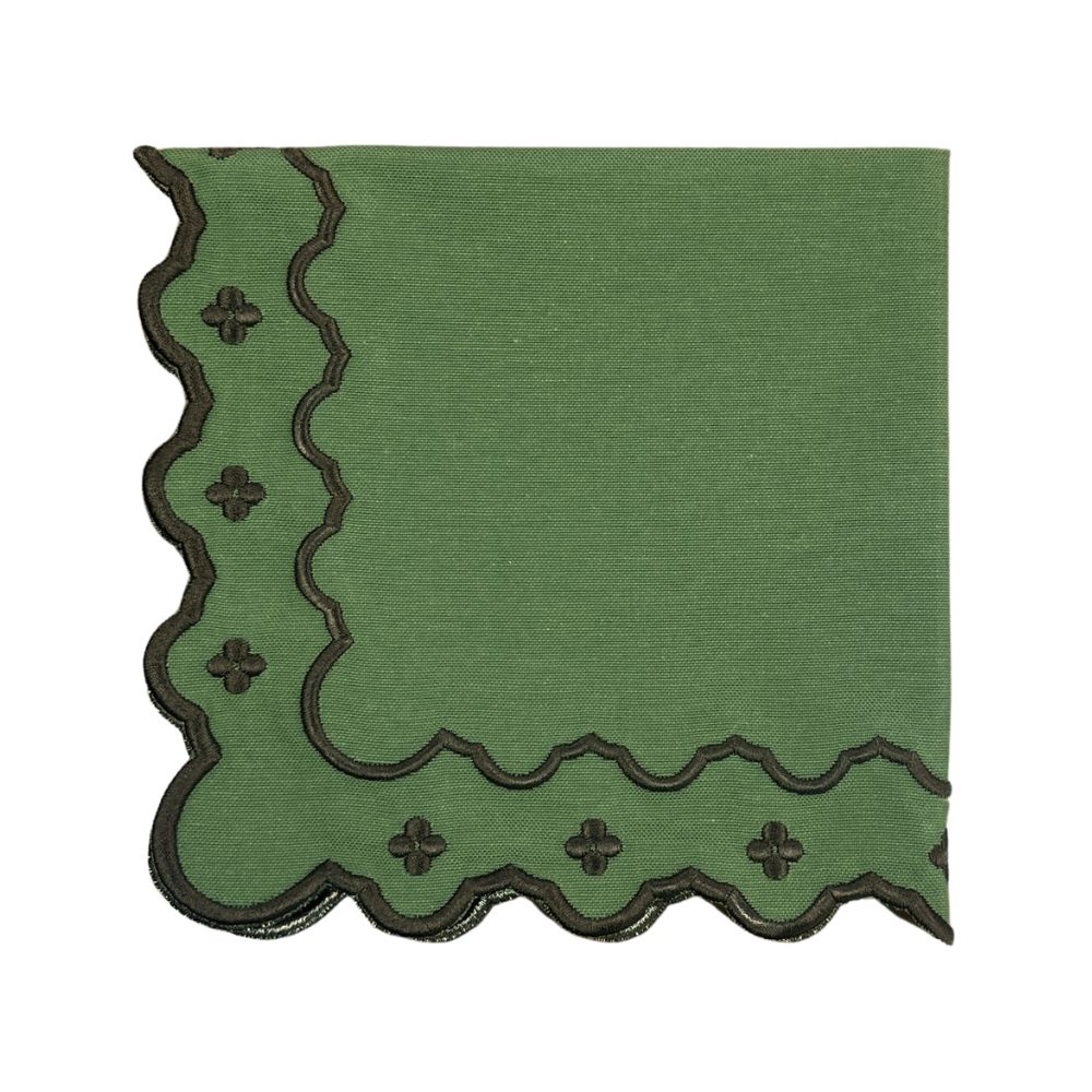 A square green linen napkin with scalloped edges and embroidered dark brown cross motifs along the border, shown on a plain white background.