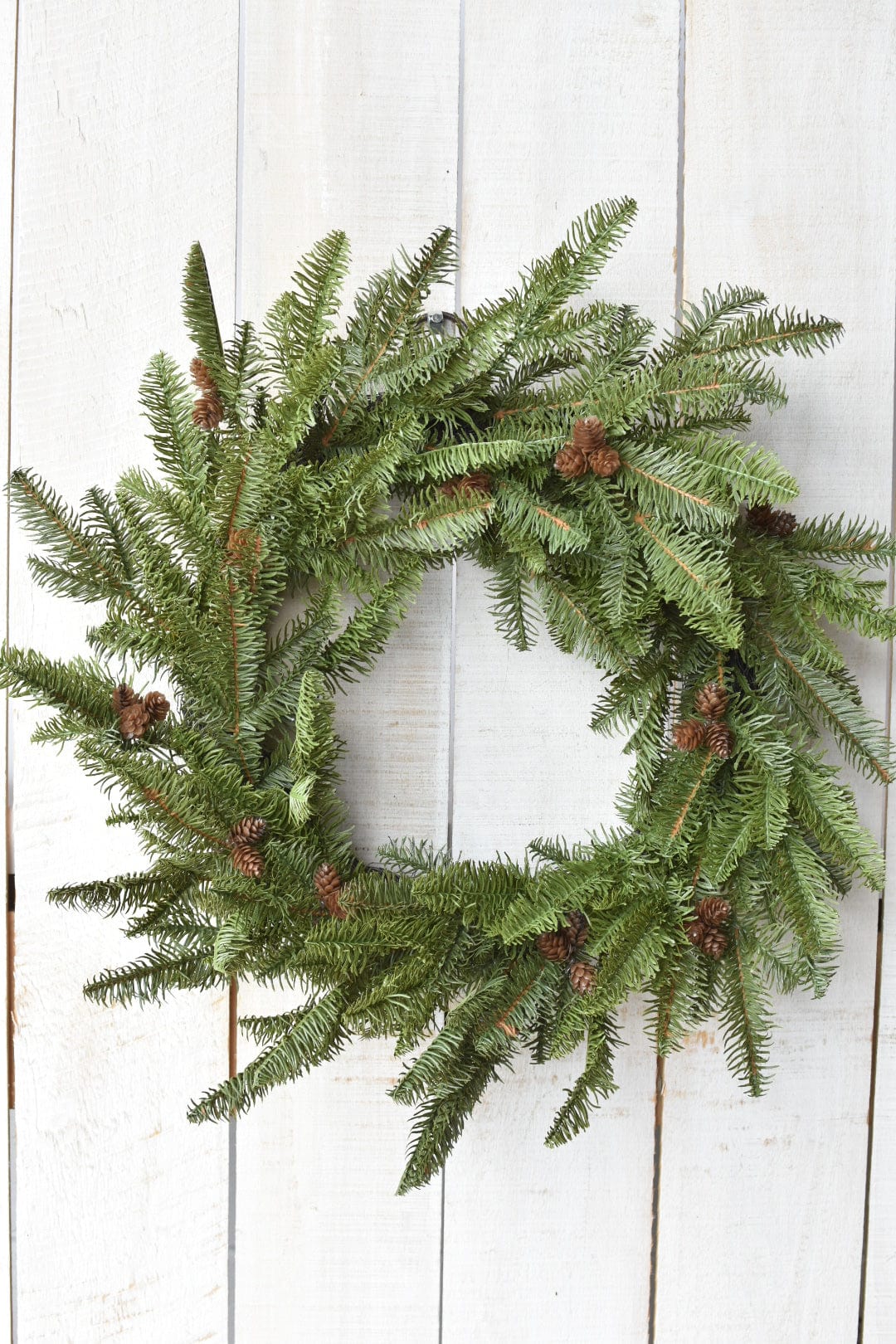 Green Christmas wreath with pinecones on a white wooden background