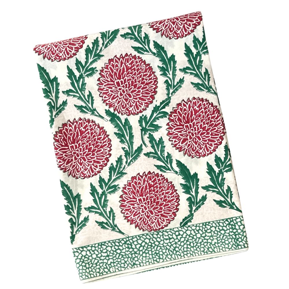 A folded cotton tea towel with a block-printed floral pattern featuring red chrysanthemums and green leaves on an off-white background, with a matching green patterned border.