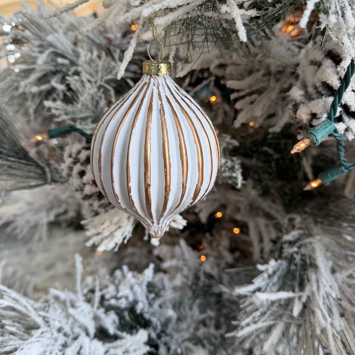 Decorative ornament on a frosted Christmas tree with lights.