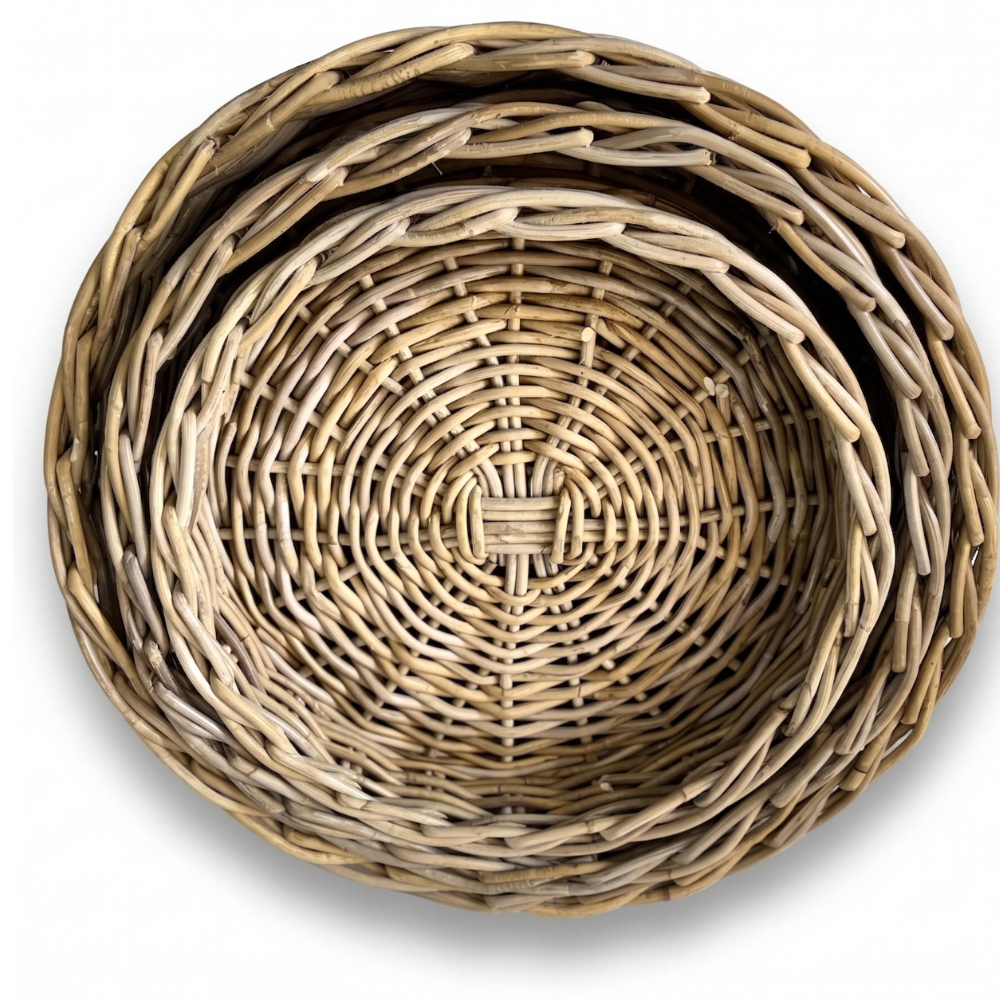 Three nested round woven baskets made from natural light brown wicker or rattan, shown from a top-down view on a white background.