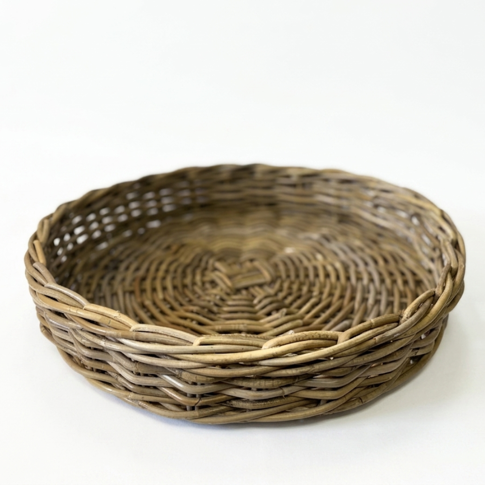 A round woven wicker tray with a natural brown and beige color palette, photographed on a seamless white background.