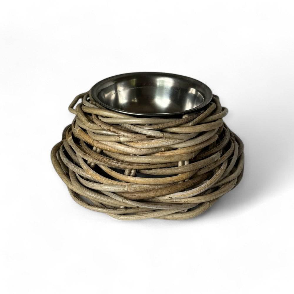 A rustic pet bowl elevated on a woven wicker basket base, featuring a brushed stainless steel bowl nested inside a circular wicker frame, set against a plain white background.