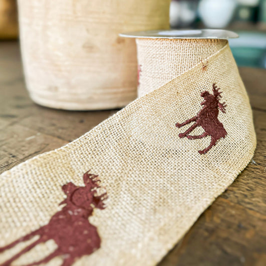 Burlap ribbon with printed deer design on a wooden surface