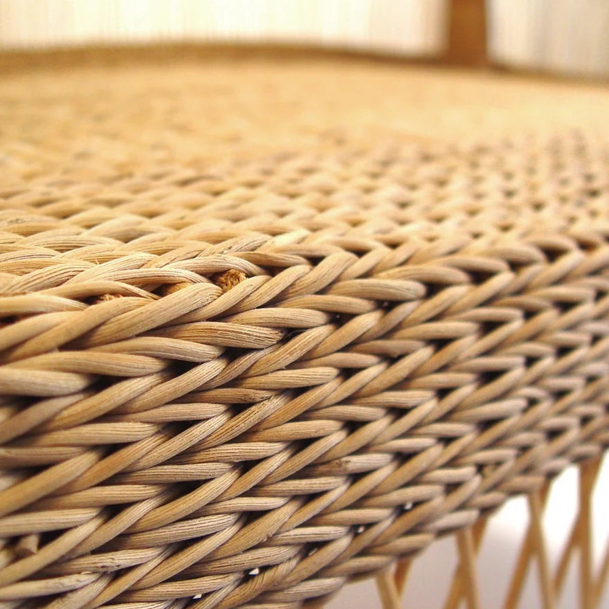 Close-up of a woven rattan or wicker surface with a tight basketweave pattern in warm natural tan and light brown tones.